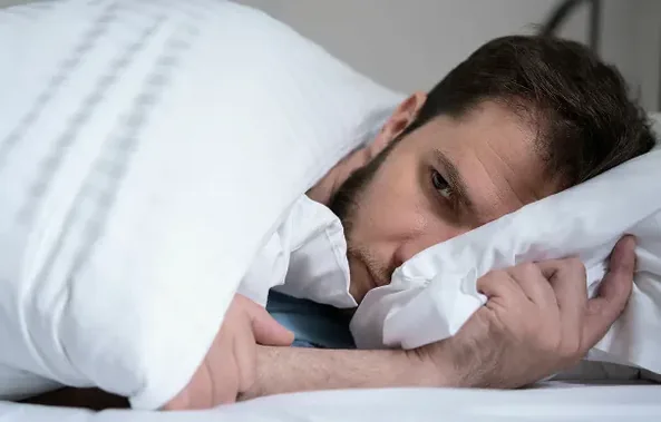 Man lying awake in bed with his head on the pillow