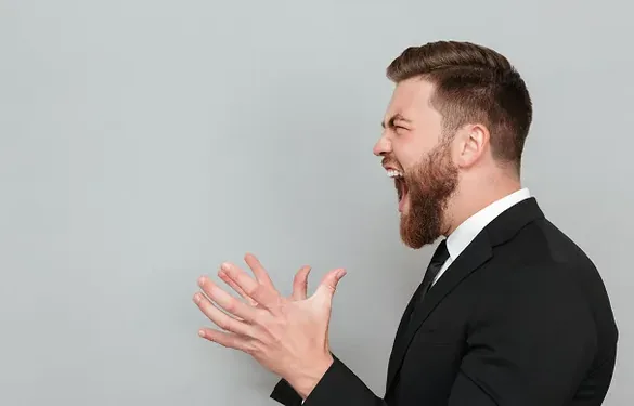 Man in a suit raising his voice, showing rising tension